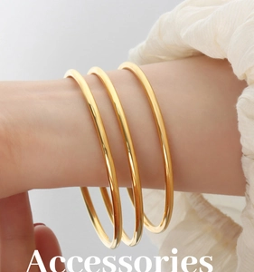 Close-up of three minimalist polished gold-plated titanium steel bangles on model's wrist