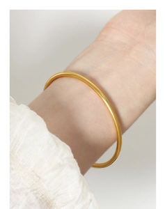 Close-up of a minimalist gold-plated titanium steel thin bangle on a female wrist