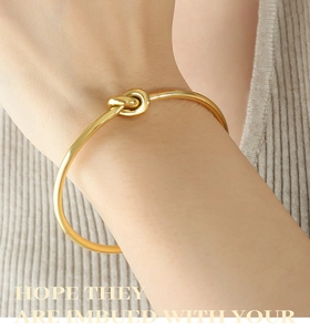 Primo piano di un bracciale con nodo dorato placcato oro 18K indossato sul polso
