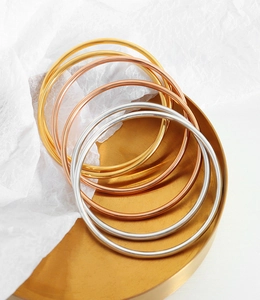 Detailed shot of minimalist thin bangles in gold, silver, and rose gold on a tray