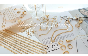 Flat lay of multiple 18K gold plated steel jewelry pieces with various fashion pendants