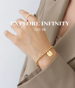 Detailed view of 18K gold bead bracelet with engraved square charm and pearl ring