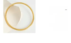 Detailed view of a minimalist thin gold bangle with a polished mirror finish