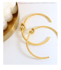 Dettaglio di orecchini a nodo placcati in oro 18K con finitura metallica lucida a specchio