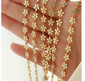 Macro view of dainty golden flower chains with light blue enamel heart and petals