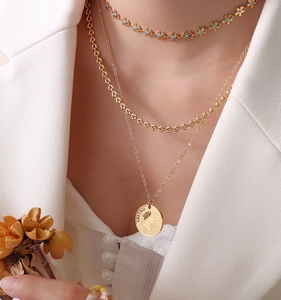 Close-up of a three-layer gold necklace set featuring a coin pendant and blue flower charm
