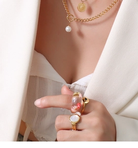 Detail of 18K gold-plated coin necklace with pearls and resin dried flower ring on a model