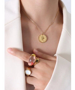 Detail of 18K gold coin necklace and resin ring with dried flowers and heart pattern