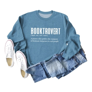 Flat lay of gray-blue Booktrovert sweatshirt with white text print and lifestyle props
