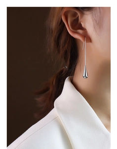 Detail of elegant silver teardrop earrings on model with polished metal finish
