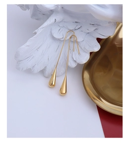 Detailed close-up of golden teardrop pendant earrings hanging on white wings ornament
