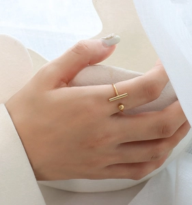 Close-up of minimalist gold T-bar open ring on hand with soft elegant background