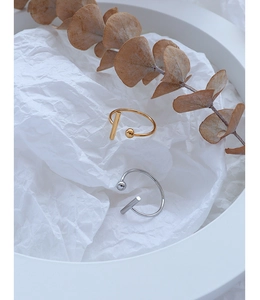 Minimalist T-shaped open rings in gold and silver finish on a white decorative tray