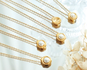 Detail van vintage gouden kettingen met onregelmatige parels op een spiegelend oppervlak