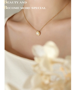 Detail van 18K vergulde ketting met parelhanger gedragen door een model op de foto