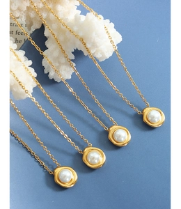 Detail van vijf 18K vergulde titanium kettingen met schelpparels op elegante achtergrond