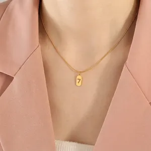 18K vergoldete Schlangenkette mit Glückszahl 7 Anhänger, getragen zu einem pfirsichfarbenen Anzug