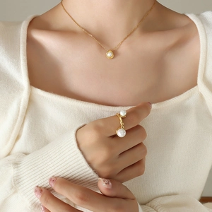 18K vergulde titanium ketting en dubbele parelring set gedragen door een model