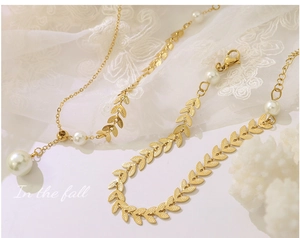 Detail von goldenem Weizenblatt-Schmuckset mit Perlen auf romantischem Spitzenhintergrund