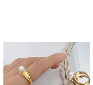 Vue détaillée d'une bague géométrique dorée avec perle blanche sur miroir
