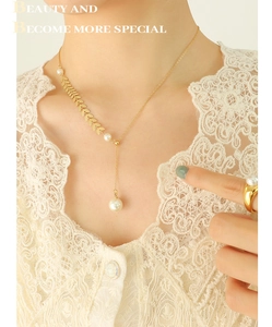 Detail eines eleganten Gold-Perlen-Sets aus Halskette und Ring mit Spitzenbluse