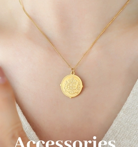Detailed view of an 18k gold plated coin pendant necklace with embossed vintage crest