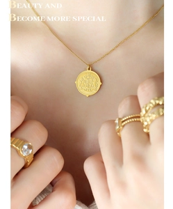 Close-up of a vintage golden coin pendant necklace with an intricate embossed emblem