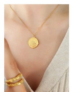 Close-up of a 18k gold plated medallion necklace featuring a vintage embossed coin pendant