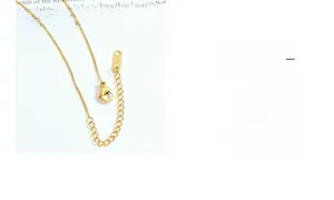 Detailed close-up of golden necklace lobster clasp and K18 engraved tag on white background