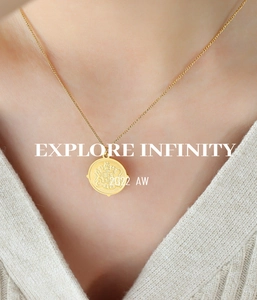 Detail of a gold coin pendant necklace with embossed crest on 18k plated titanium steel