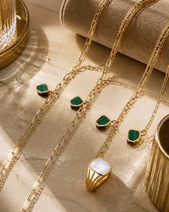 Detail van 18K vergulde titanium ketting met groene steen en vierkante schelpring