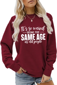 Detail of burgundy sweatshirt with white 'It's so weird' slogan text and cotton texture