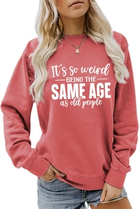 Detail of rust red sweatshirt with 'It's so weird' slogan and ribbed cuff texture