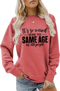 Detail of It's so weird slogan print on brick red long sleeve crewneck sweatshirt
