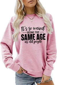 Detailed view of pink crewneck sweatshirt with It's so weird text print on cotton fabric