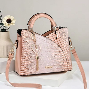 Rosa Handtasche mit Krokodilprägung, Herzanhänger und Schultergurt auf weißem Podest