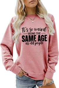 Detail of pink crewneck sweatshirt with It's so weird being the same age text