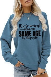 Close-up of blue long sleeve sweatshirt featuring It's so weird slogan and drop shoulder detail