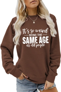 Detail of dark brown sweatshirt featuring white 'It's so weird' slogan and ribbed collar