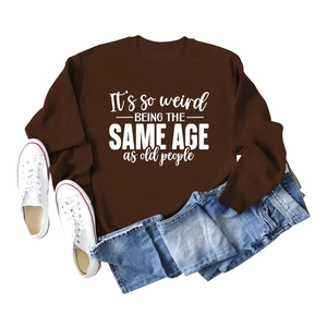 Flat lay of brown long sleeve sweatshirt with white slogan and washed blue jeans
