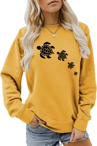 Close-up of ginger yellow sweatshirt featuring four black sea turtle silhouettes printed on front