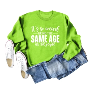 Neon green sweatshirt detail with white 'It's so weird' text print and casual styling