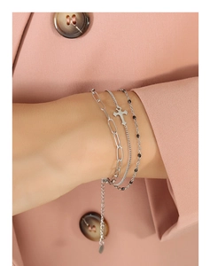 Close-up of triple-layered silver cross bracelet with paperclip chain and black beads
