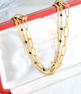 Macro view of gold layered cross necklace with black beads and paperclip chain details