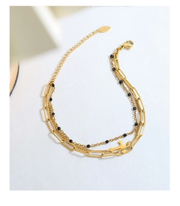 Close-up of triple-layered gold cross bracelet with black beads and 18K hallmark tag
