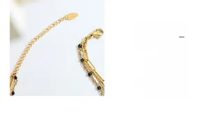 Close-up of K18 gold layered bracelet featuring lobster clasp and black bead accents