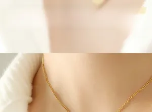 Gros plan d'un collier à maillons fins dorés minimaliste porté par une femme