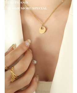 Détail d'un collier serrure porte-bonheur dorée avec gravure et bagues assorties