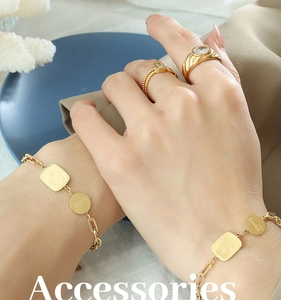 Détail du bracelet doré avec pendentif dessin animé et breloque chance au poignet du mannequin