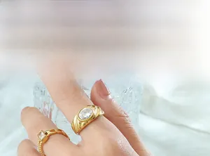 Détail d'une bague torsadée avec zircon ovale et bague chaîne en finition or 18 carats